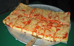 Thick-crusted, rectangular pizza topped with tomato sauce and cheese