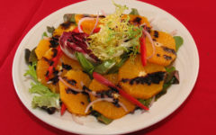 Salad plate includes slices of orange drizzled with dark balsamic vinaigrette.