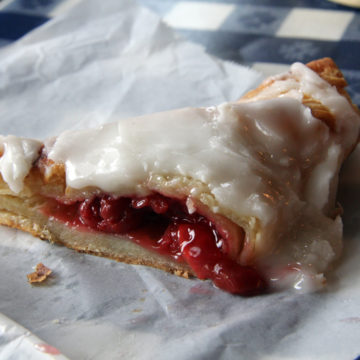 Split open cherry turnover is gilded with white sugar frosting