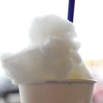 Frosty lemon-flavored slush rises high above the paper cup that contains it.