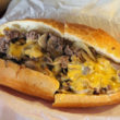Long roll holds shredded beef, molten cheese, and grilled onions