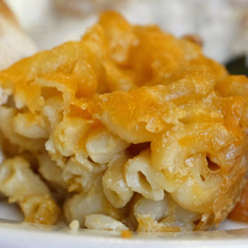 Block of baked mac & cheese shows a chewy top and creamy middle
