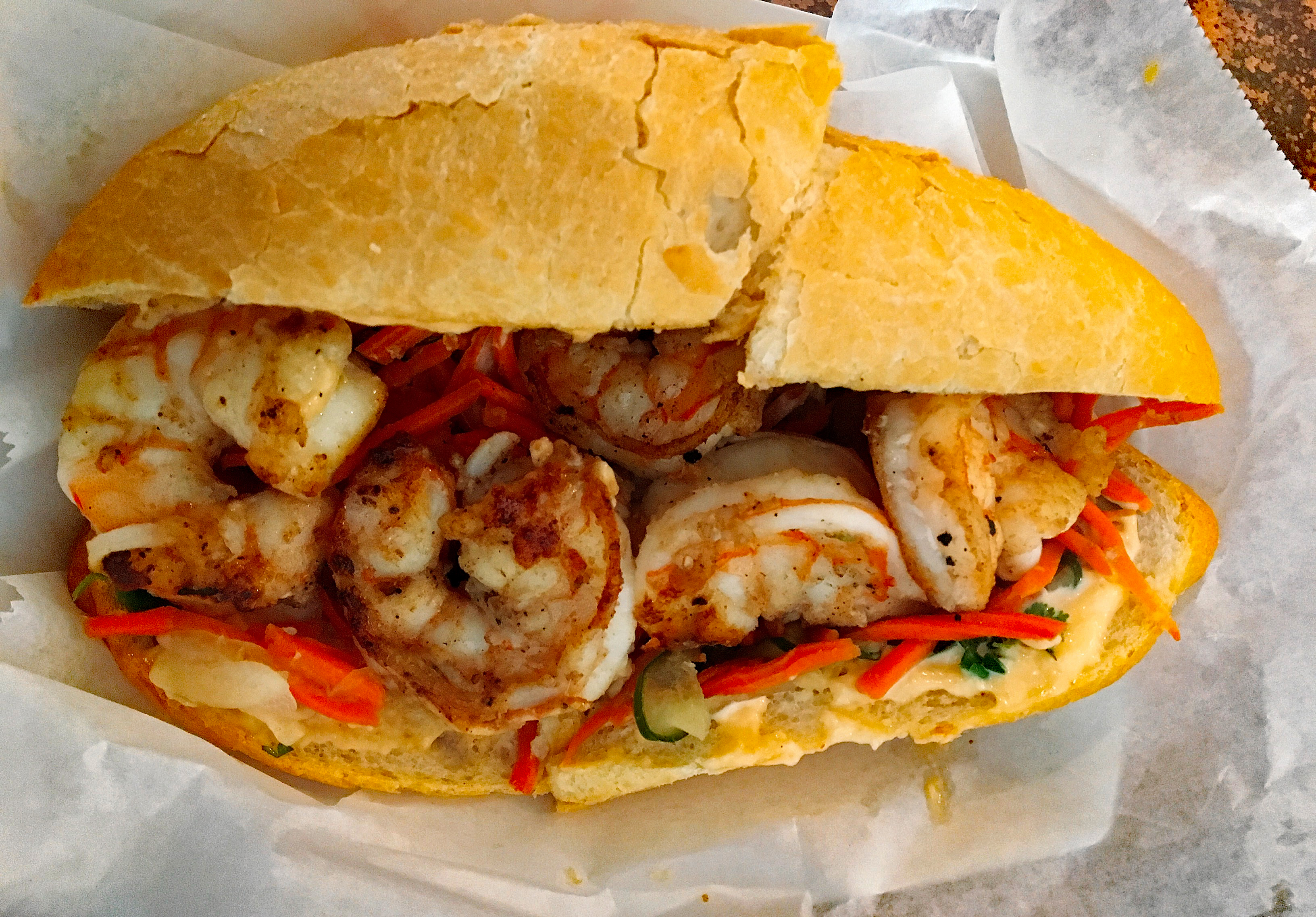 Long bun is packed with seared shrimp and colorful garnishes