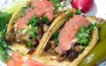 Carnitas tacos are topped with coral-pink salsa