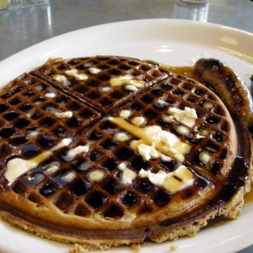 Dark gingerbread-corn waffle is accompanied by chicken sausage links and topped with butter and syrup