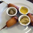 Three corn dogs with three kinds of mustard for dipping