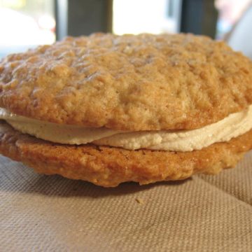 A pair of oatmeal cookies sandwich molasses cream