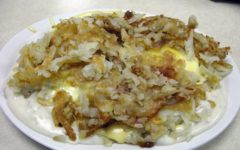 Eggs and breakfast meats are buried under a mound of hash browns, cheese sauce, and gravy.