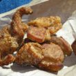 Golden-crusted, irregularly-shaped bite-size pieces of cracklin are eaten off the paper bag in which they were purchased.