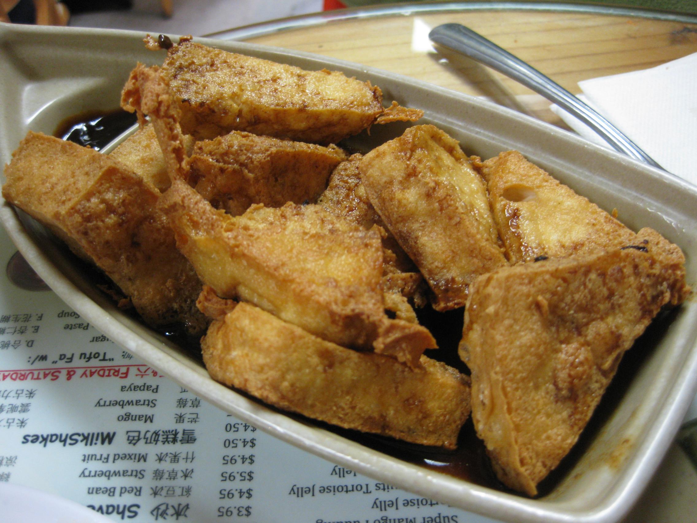 Plate of crisp-fried tofu triangles waiting to be dipped in sauce