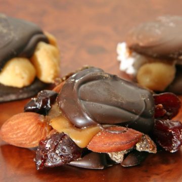 Peeking out from under the chocolate shell of a candy turtle are almonds, caramel, and dried cherries and apricot