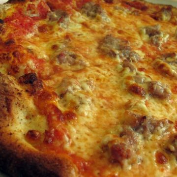 Extreme close-up of sausage bites in a drift of melted cheese on a thin-crust pizza