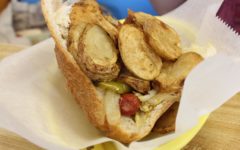 Hot dog in an opened-up half-loaf is piled with fried potatoes and vegetabls.