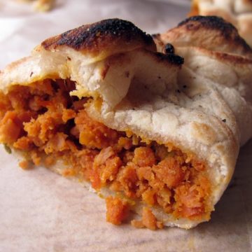 Cross section of a bread roll baked around a filling of chili-red crumbled sausage