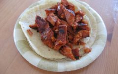Spice-red chorizo sausage spread out on tortillas on a paper plate