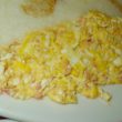 Yellow scrambled eggs are mixed with pink nuggets of brain.