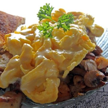 Cheese-infused scrambled eggs atop fried potatoes and sausage
