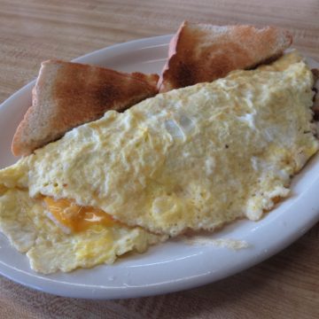 Cheese peeks out of an omelet that also contains hash browns and sausage