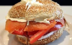 Sesame bagel is stuffed with lox, tomato slices, and cream cheese.