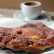 Flat, sugar-dusted disk of quick-fried pastry with a cup of espresso