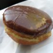 Holeless donut is sliced, loaded with custard and frosted with dark chocolate