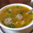 Little meatballs float with herbs in bowl of savory soup