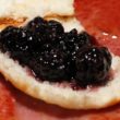 Dark-purple blackberry preserves atop the bottom of a split biscuit