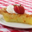 Slender wedge of clear chess pie is topped with a strawberry and whipped cream