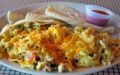 In addition to its tortilla chips, this migas contains veggies and is topped with melted cheese