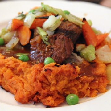 Beef stew with plenty of vegetables, shored in by a wall of mashed sweet potatoes