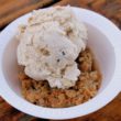 Apple crisp in a bowl is topped with maple walnut ice cream.