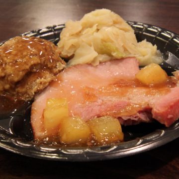 Disposable plate holds pineapple glazed baked ham, stuffing, and potatoes