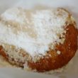A fry-browned biscuit is smothered with a thick blanket of powdered sugar