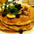 A stack of buttermilk blueberry pancakes is scattered with granola