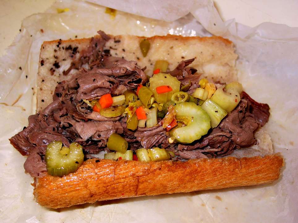 Gravy-sopped Italian beef piled into a length of bread with spicy vegetable giardiniera