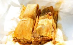 Two tamales, wrapped in corn husks, bask in the sun