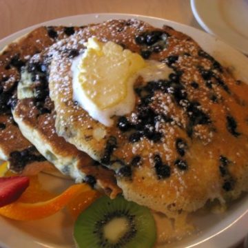 Stack of pancakes loaded with blueberries and spread with butter