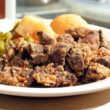 Gnarly fried chicken livers are piled on a plate with vegetables in the background
