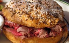 Thin-sliced roast beef is piled into a bun that is plastered with caraway seeds and coarse salt