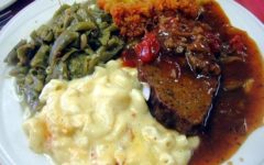 Meat loaf is on a plate crowded with green beans, squash casserole, and mac & cheese