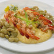 A plate of creamy grits, topped with shrimp and sided by butter beans
