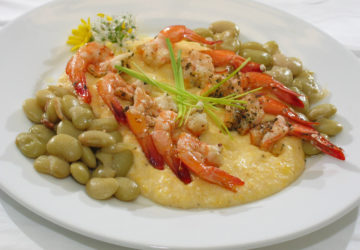A plate of creamy grits, topped with shrimp and sided by butter beans