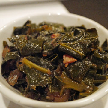 A bowl of soft-cooked collard greens shows bits of pork