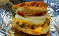 Piled-high burger includes lettuce, tomato, mayonnaise, and melted cheese.