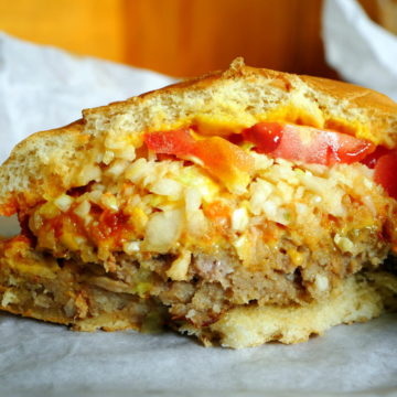 Hamburger, infused with breadcrumbs is bunned along with cheese, tomatoes, et al.