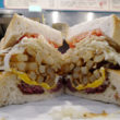 Mountainous sandwich holds pastrami, egg, French fries, cole slaw, and a tomato at Primanti Brothers in Pittsburg, PA