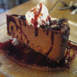 A triangle of dark, supersweet chocolate cheesecake drips with Kahlua and raspberry puree