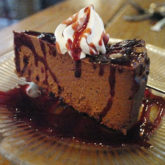 A triangle of dark, supersweet chocolate cheesecake drips with Kahlua and raspberry puree