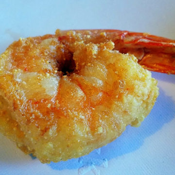 A single fried shrimp with crisp crust so thin you can see through it.