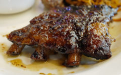 A cluster of baby back ribs is glazed with dark, sweet sauce.